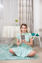 Sexy model girl in a beautiful interior studio shows a photographer a gray card