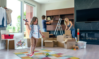 Little boy playing with a toy airplane while his parents unpack moving boxes
