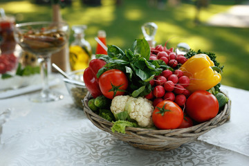 A lot of a vegetables arranged in a basket on the table outside.