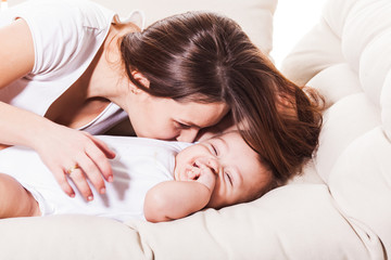 Obraz na płótnie Canvas Mother kisses and hugs her baby