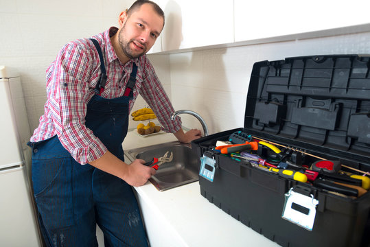 Handsome man standing in the kitchen with his toolbox