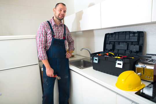 Handsome man standing in the kitchen with his toolbox