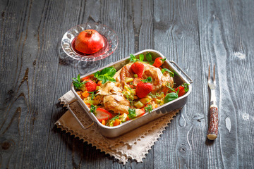 Whole wild rabbit backed in pomegranate juice with strawberry, vegetables, spices and herbs in metallic dish on old black rustic wooden background. Clean eating, healthy food and diet concept