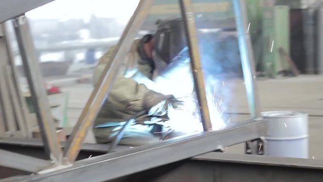 industrial worker welds a metal frame
