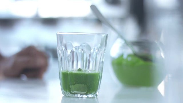 matcha tea preparation in glass with electric blender mixer