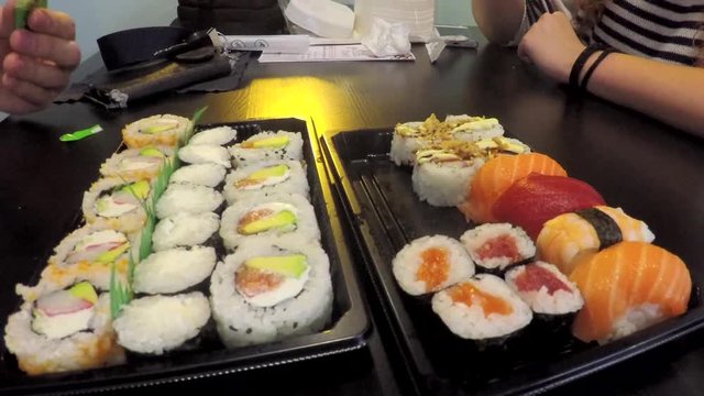 This is footage of a couple, no faces or recognizable features visible, eating at a sushi joint, some very tasty sushi rolls.
