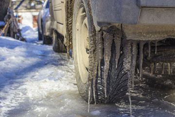 Extreme winter series. Car in ice. Icicles on a wheel arch close-up.