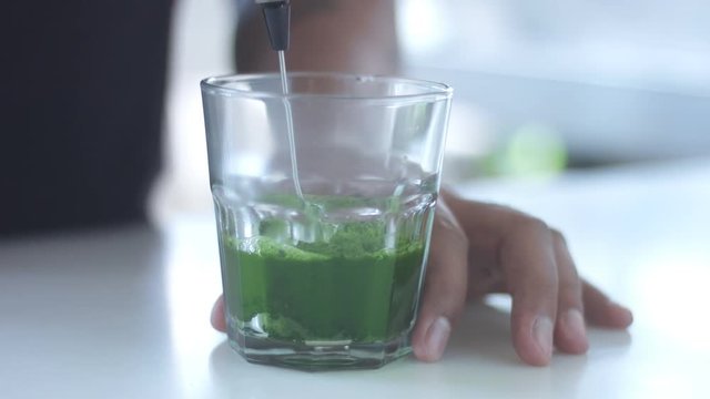 strong green matcha tee in transparent glass preparation process