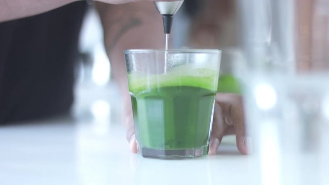 strong green matcha tee in transparent glass preparation process