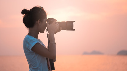 young woman photographer, taking pictures of landscape at sunset