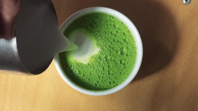 top view of milk pouring in cup with matcha tee Matcha latte preparation