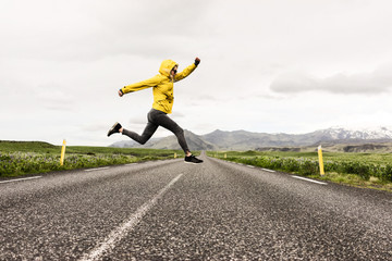 Woman jumping over the middle of a road