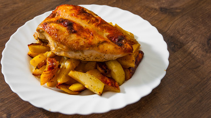 roasted chicken breast with potato in a plate on wooden table