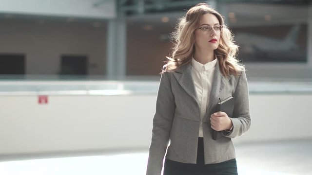 confident business woman walking through the lobby of a modern office building