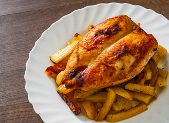 roasted chicken breast with potato in a plate on wooden table