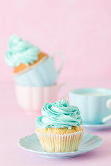 Cupcake with mint cream decoration and cup of milk and coffe on pink pastel background. Mother's day greeting card