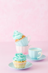Cupcake with mint cream decoration and cup of milk and coffe on pink pastel background. Mother's day greeting card