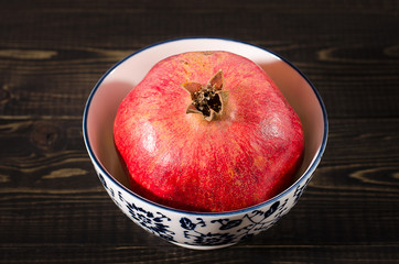 one ripe pomegranate on a black wooden background