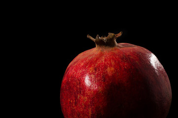 one ripe pomegranate on a black background