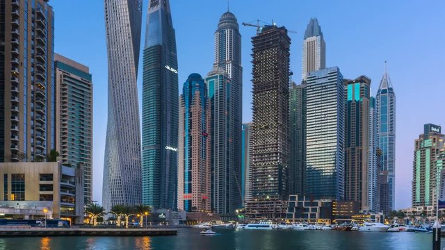 beautiful view from promenade on Dubai Marina tallest modern towers and floating yachts and boats timelapse at sunset.