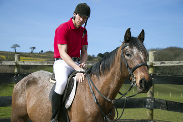 Handsome horse rider on horseback in paddocks with blue sky 