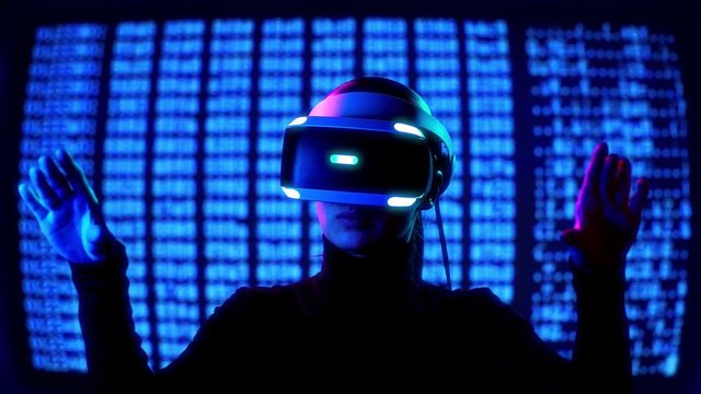 Young female in VR Headset controls virtual reality by hand gestures in front of computer barcode moving background. Future tech concept