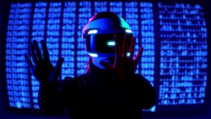 A girl in VR headset plunges into virtual reality and tries to feel herself inside and touch with her handsin fron of background of running computer binary code - Powered by Adobe