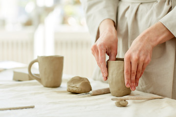 Obraz na płótnie Canvas Female hands forming mug from grey clay while working in studio of handmade production