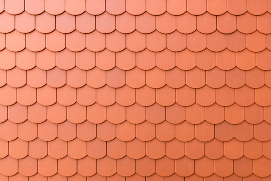 Fragment of a red roof of a private house made of shingles