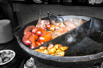 Street food - fries and pork sausages on cooking pan, Closeup. Selective focus. Copy space.