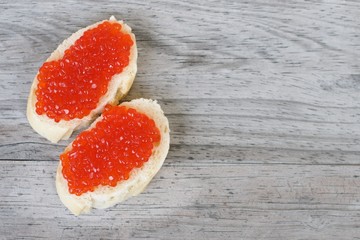 Red salmon caviar on a white bread on a wooden background