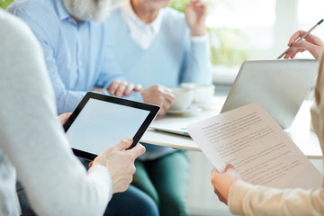 Hands of business people with touchpad and papers during presentation of new project or online data