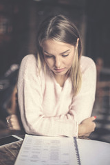 Young student girl sitting at home and reading file.
