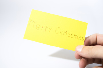 Merry christmas handwrite with a hand on a yellow paper