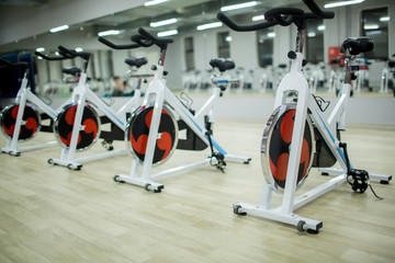 Fototapeta na wymiar Row of new sports bikes for exercising in large modern fitness center or gym