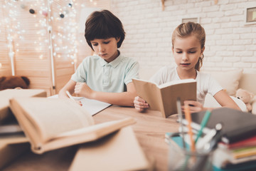 Children at home. Brother is writing and sister is reading, they are doing homework.