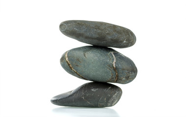 A pyramid of three stones in balance is isolated on a white background. Selective focus.