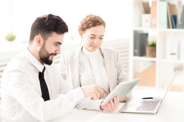 Business couple sitting at the table and using touchpad together