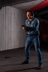 An adult man in jeans trains to shoot a gun in a closed dash.