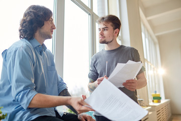 Business partners standing with documents and discussing