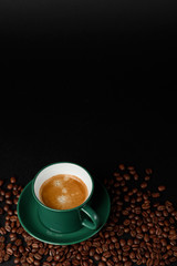 strong black coffee in a mug of emerald color on a black matte background