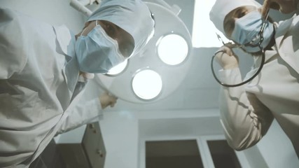 Low shot of doctor and nurse looking into a camera on patient