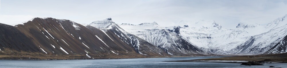 panorama of Icelandic snow capped mountain and sea in winter.