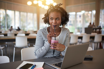 African college student drinking a smoothie on campus while stud