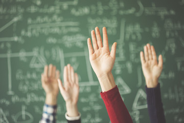 Students raised up hands green chalk board in classroom - obrazy, fototapety, plakaty