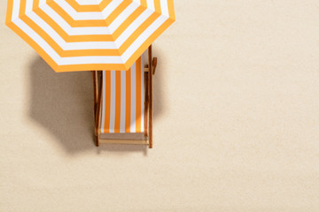 The concept of summer vacation. Top view on a sun lounger under an umbrella on the sandy beach