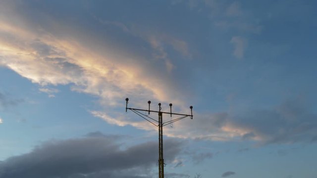 Airplane flying above a lamp posts a cloudy day at sunset