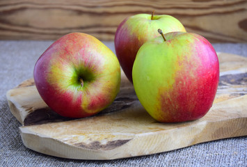Apples large, red, green are on a wooden surface.