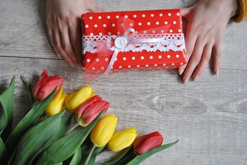 Bukiet tulipanów i prezent w kobiecych dłoniach - obrazy, fototapety, plakaty