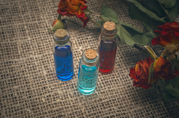 Herbal medicine concept. Bottles with color essential oils on sackcloth background.